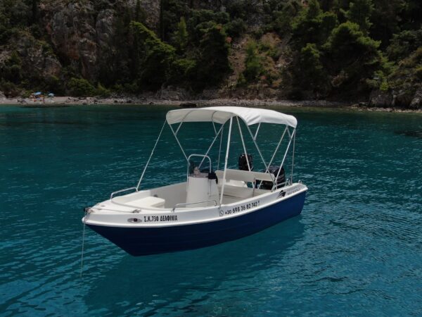 This is an image of our Kardamili Boat Rentals Delfinia Boat in Mani, with a coast full of trees at the background.