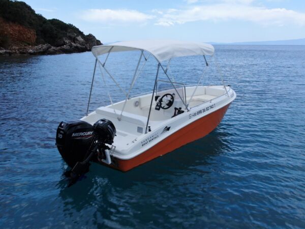 This is an image of our orange Kardamili Boat Rentals Boat, called Kalogria, at the Mani sea. At the background there is a coast with trees and rocks.