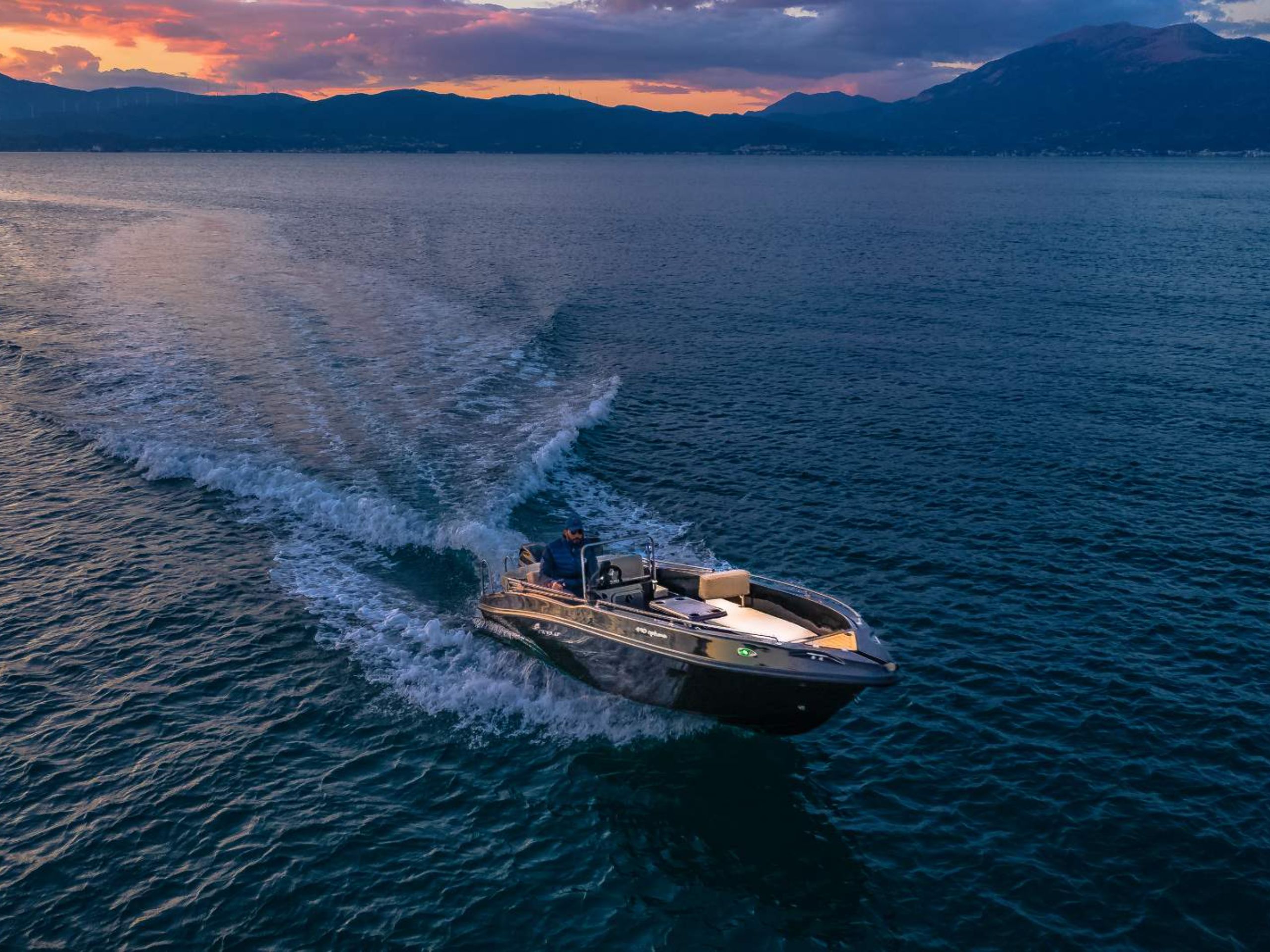 This is an image of our black Kardamili Boat Rentals boat called Meropi, cruising through dark blue waters.